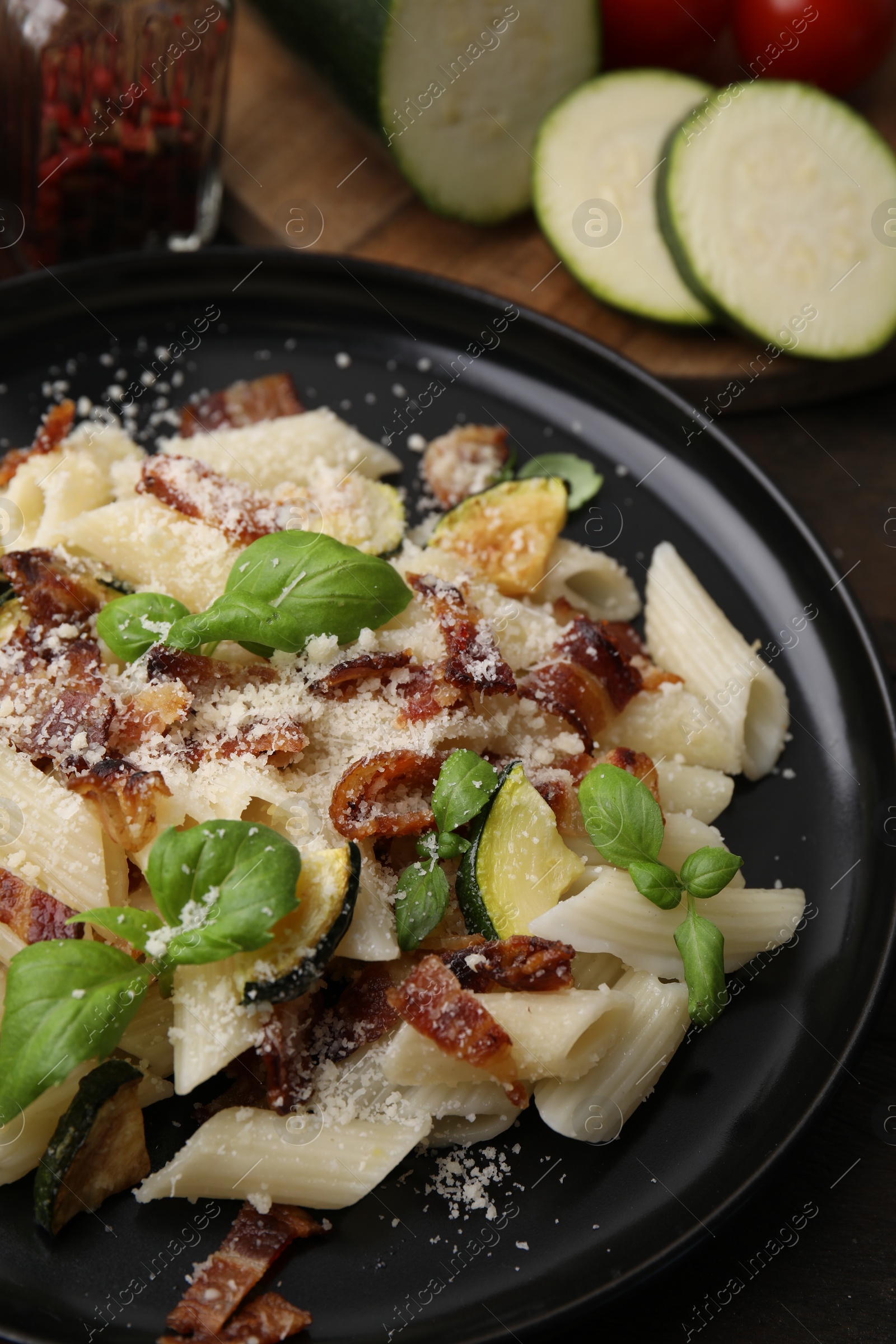 Photo of Tasty pasta with bacon and basil on wooden table, closeup