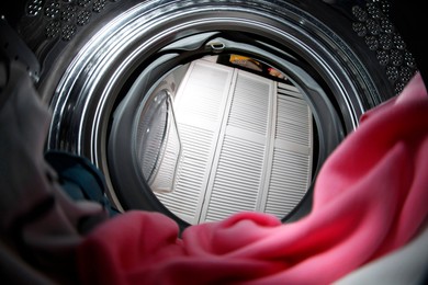 Photo of Clothes in washing machine indoors, view from inside. Laundry day