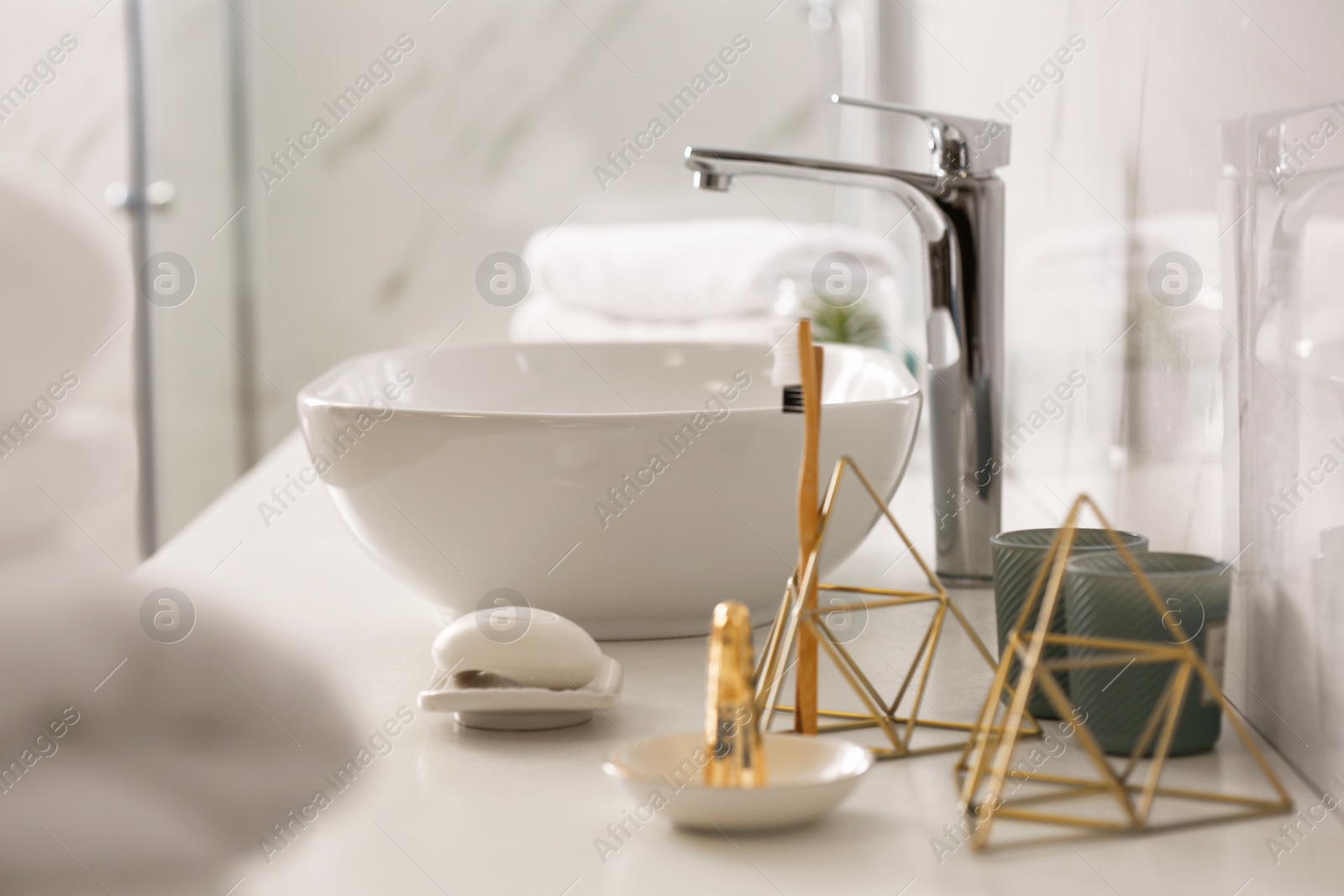 Photo of Toiletries and vessel sink on light countertop in modern bathroom