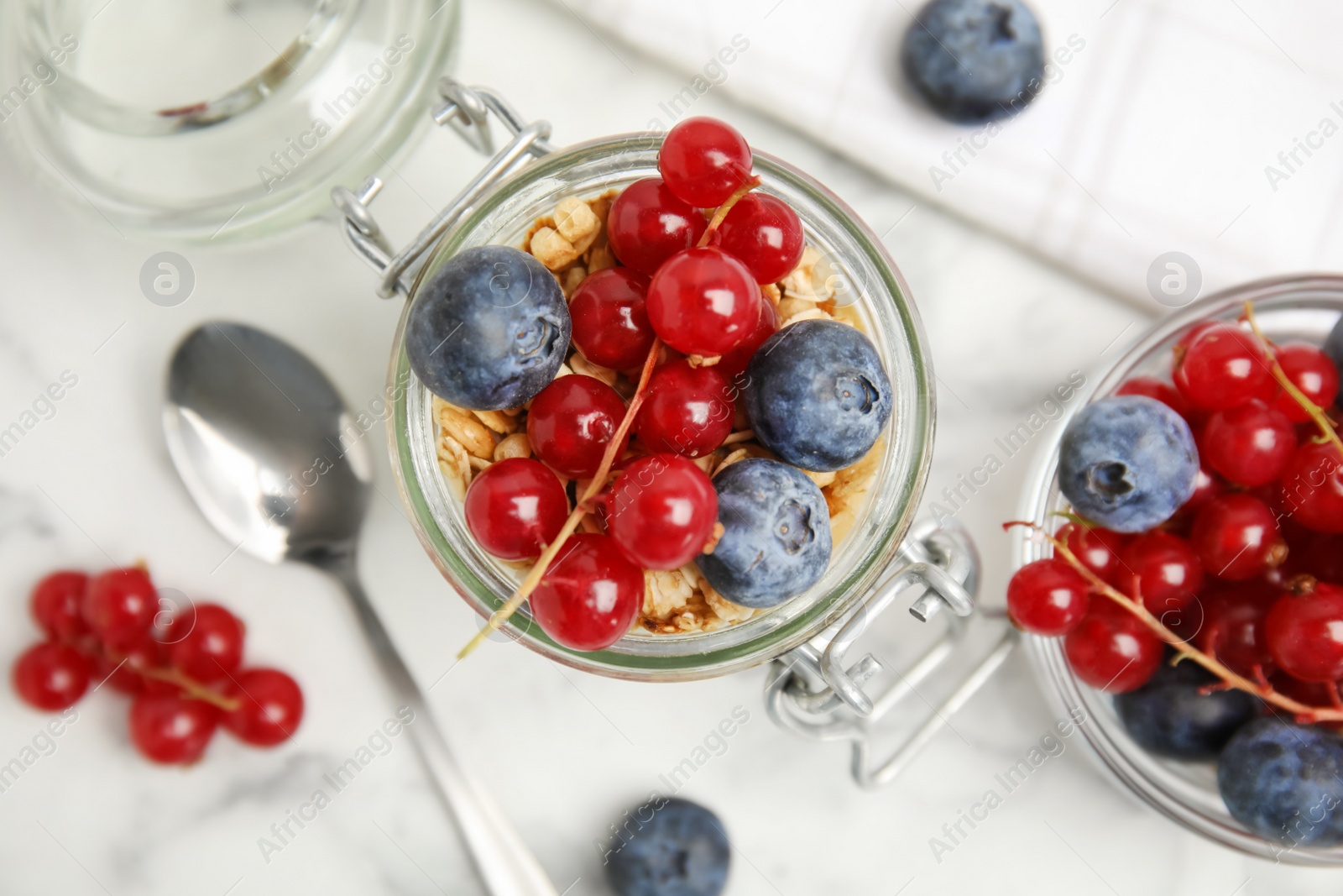 Photo of Delicious yogurt parfait with fresh berries on white marble table, flat lay