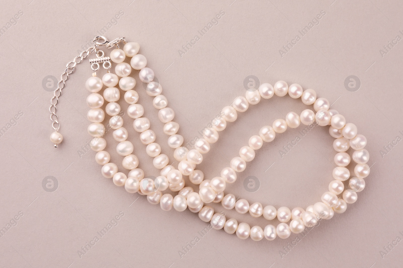 Photo of Elegant pearl necklace on beige background, top view