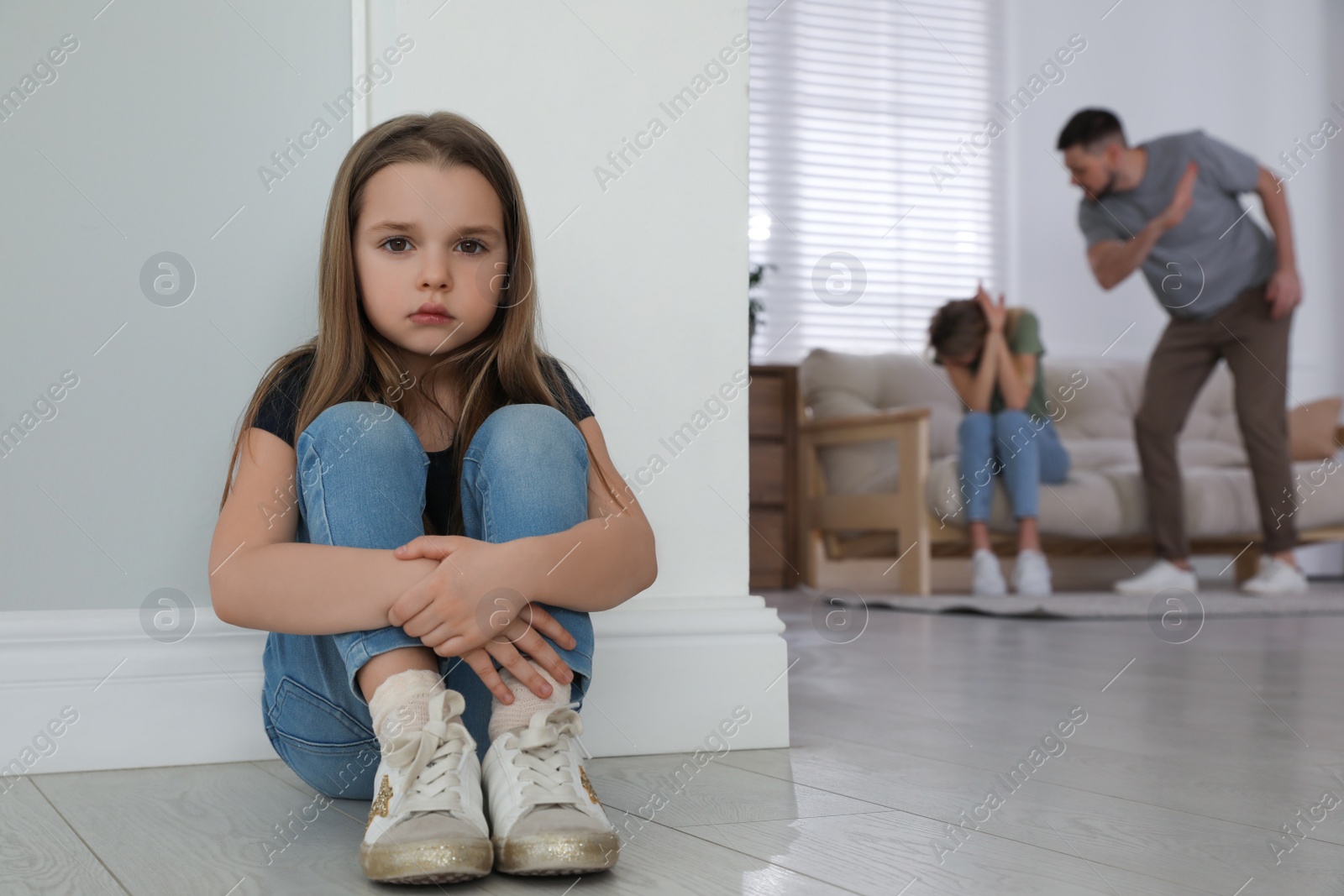 Photo of Couple fighting at home, focus on their unhappy little daughter. Domestic violence