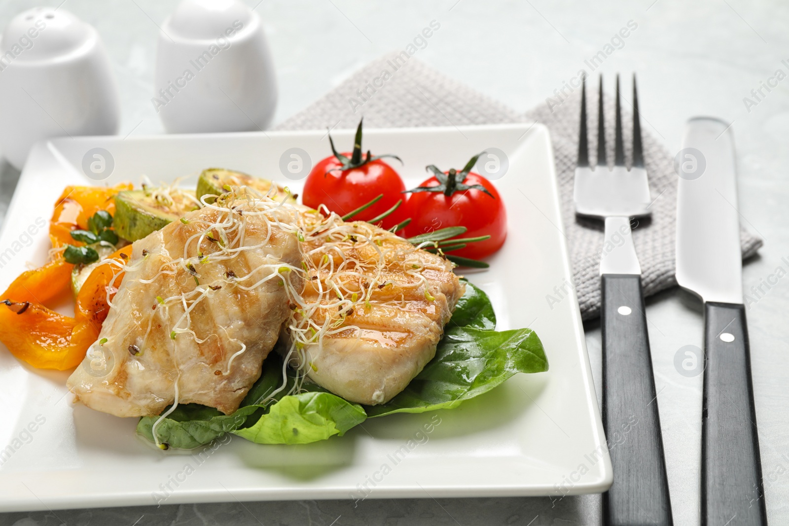 Photo of Tasty grilled fish served on light grey table