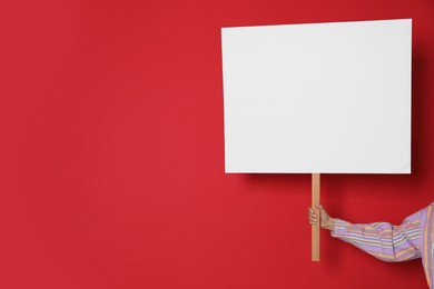 Photo of Woman holding blank sign on red background, closeup. Space for text