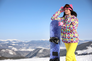 Photo of Young woman with snowboard on hill, space for text. Winter vacation