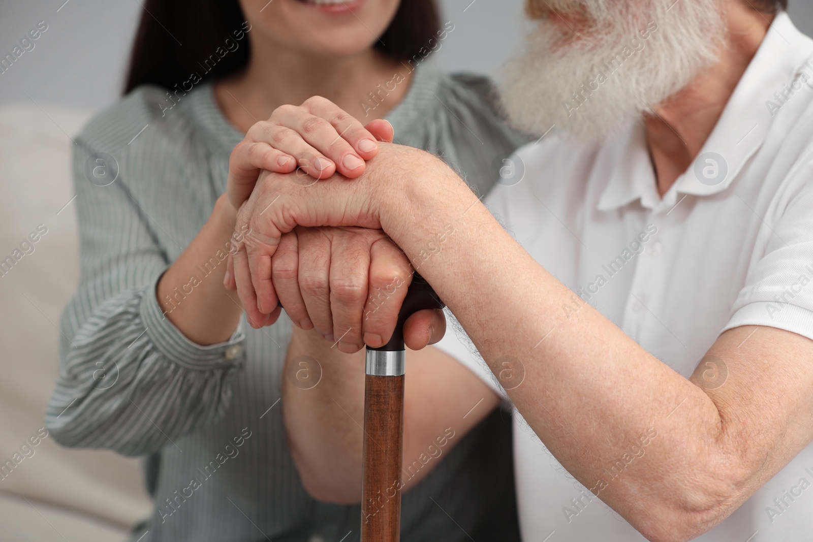 Photo of Senior man with walking cane and young woman indoors, closeup