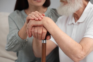 Photo of Senior man with walking cane and young woman indoors, closeup