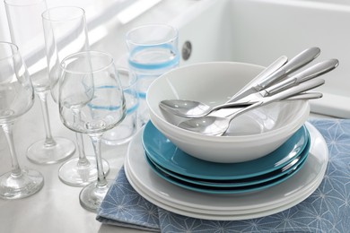 Photo of Different clean dishware, cutlery and glasses on countertop, closeup