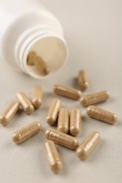 Bottle and vitamin capsules on light background, closeup