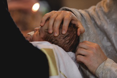 Photo of Man holding adorable baby in church during baptism ceremony, closeup