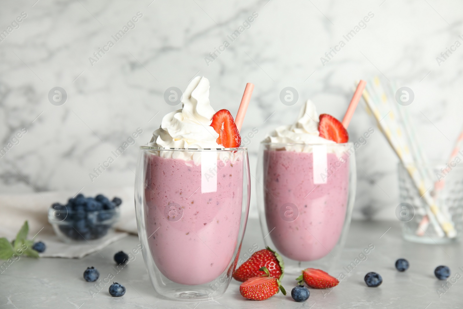 Photo of Tasty milk shakes with fresh berries on grey marble table