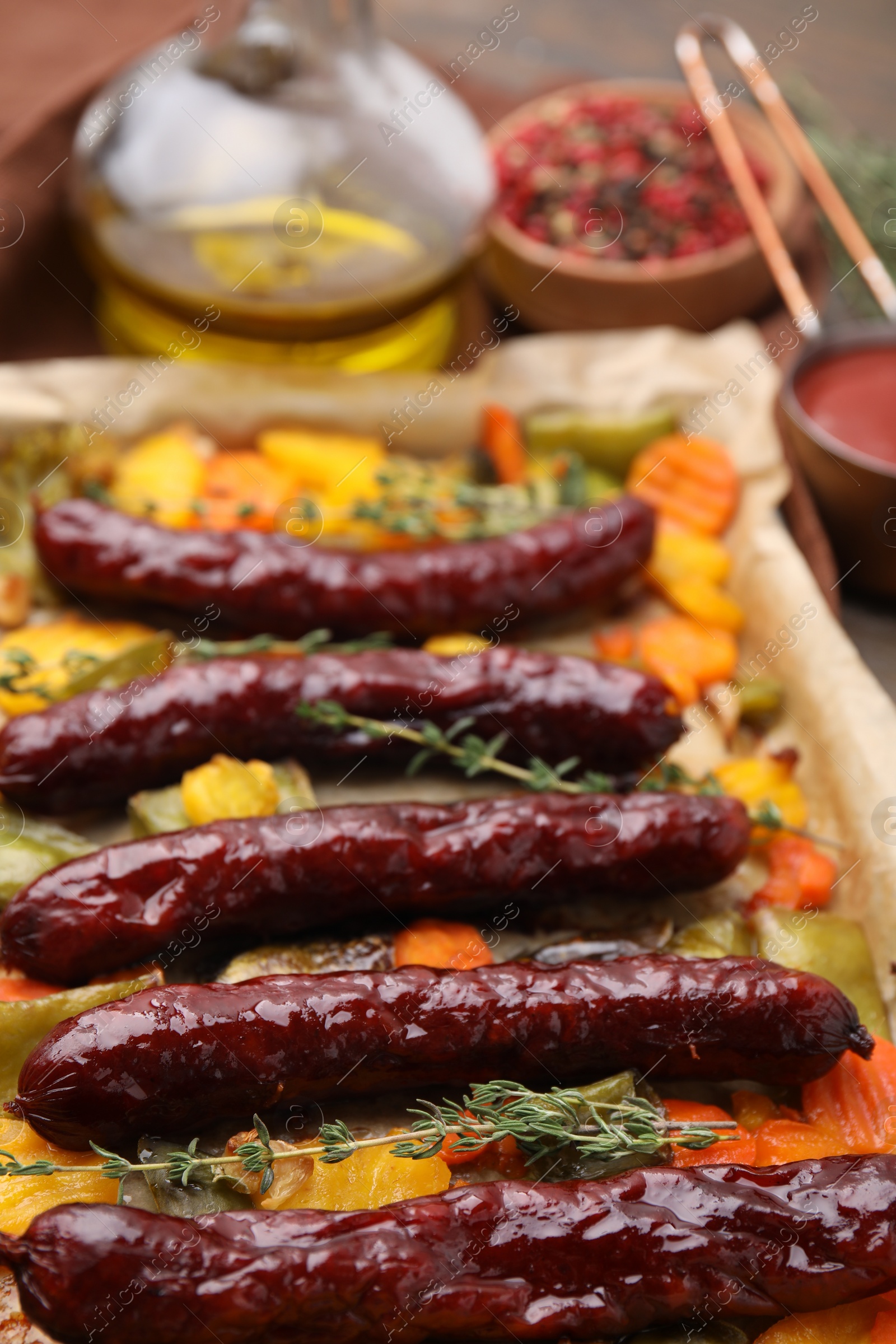 Photo of Baking tray with delicious smoked sausages and vegetables on table, closeup