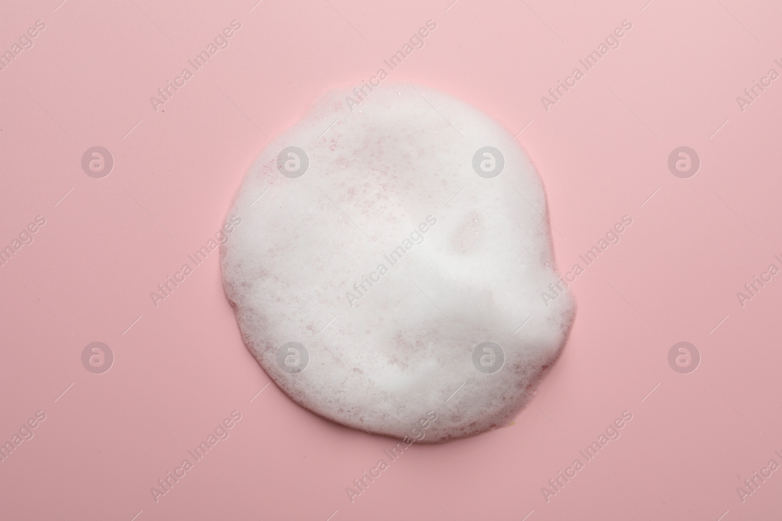 Photo of Drop of fluffy soap foam on pink background, top view