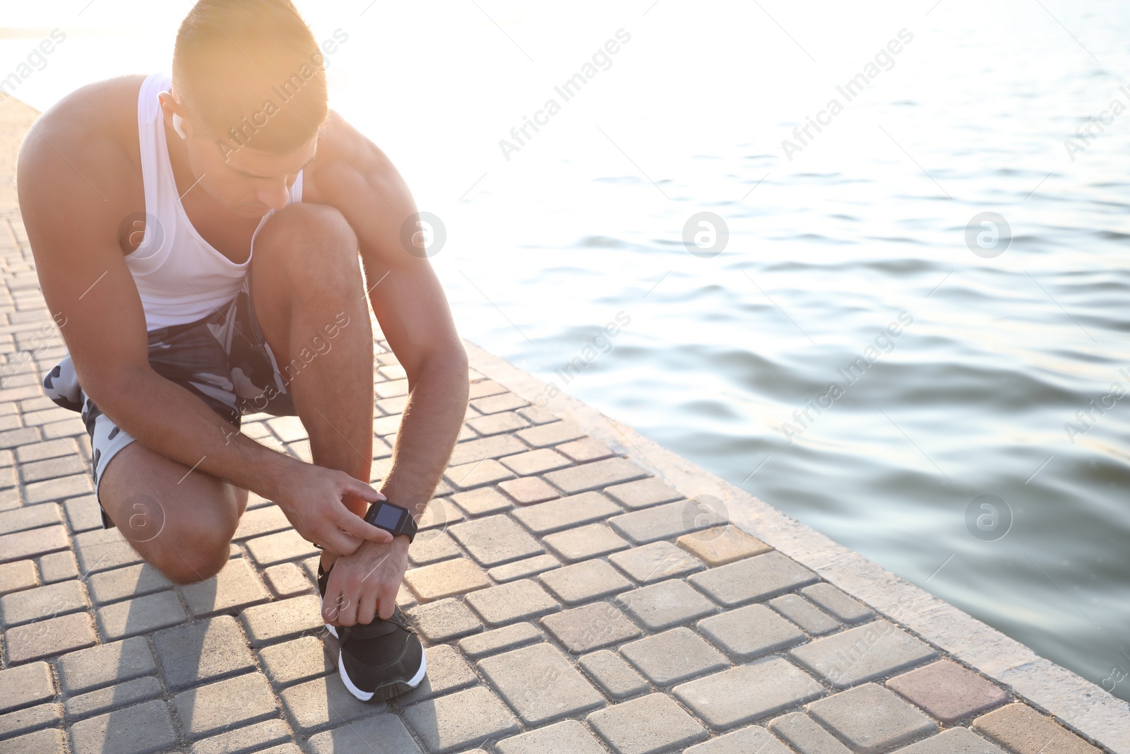 Photo of Man checking fitness tracker during training near river. Space for text