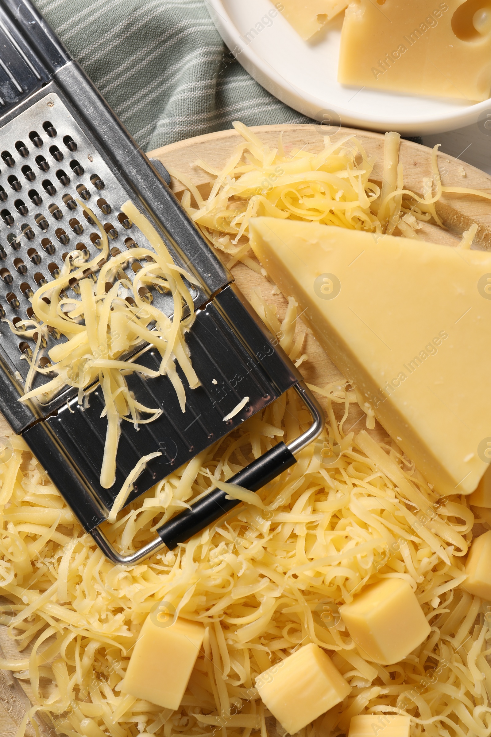 Photo of Grated, whole pieces of cheese and grater on table, top view