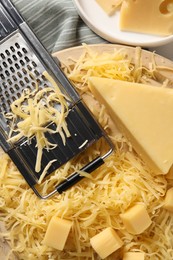 Grated, whole pieces of cheese and grater on table, top view