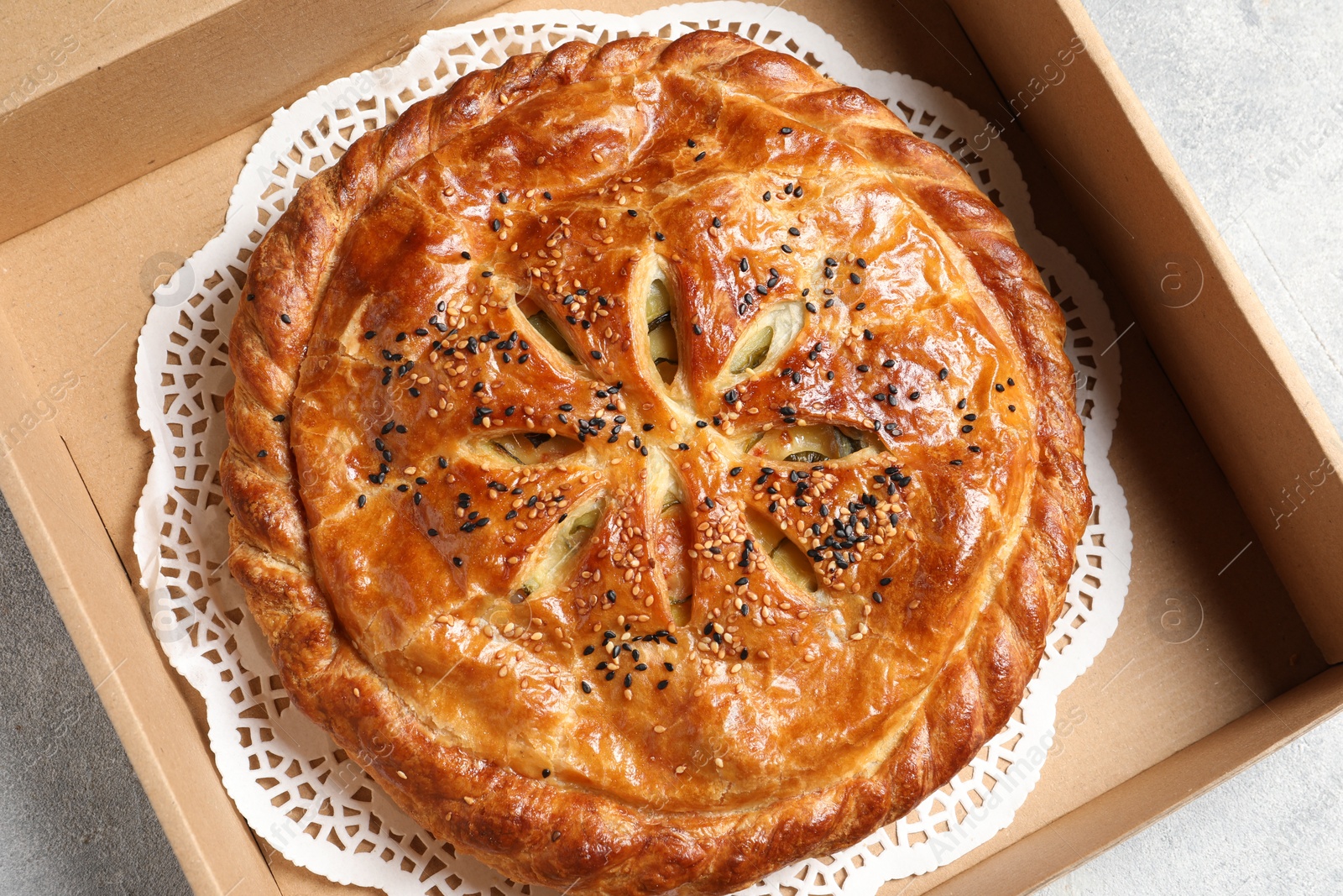 Photo of Tasty homemade pie in box on light table, top view