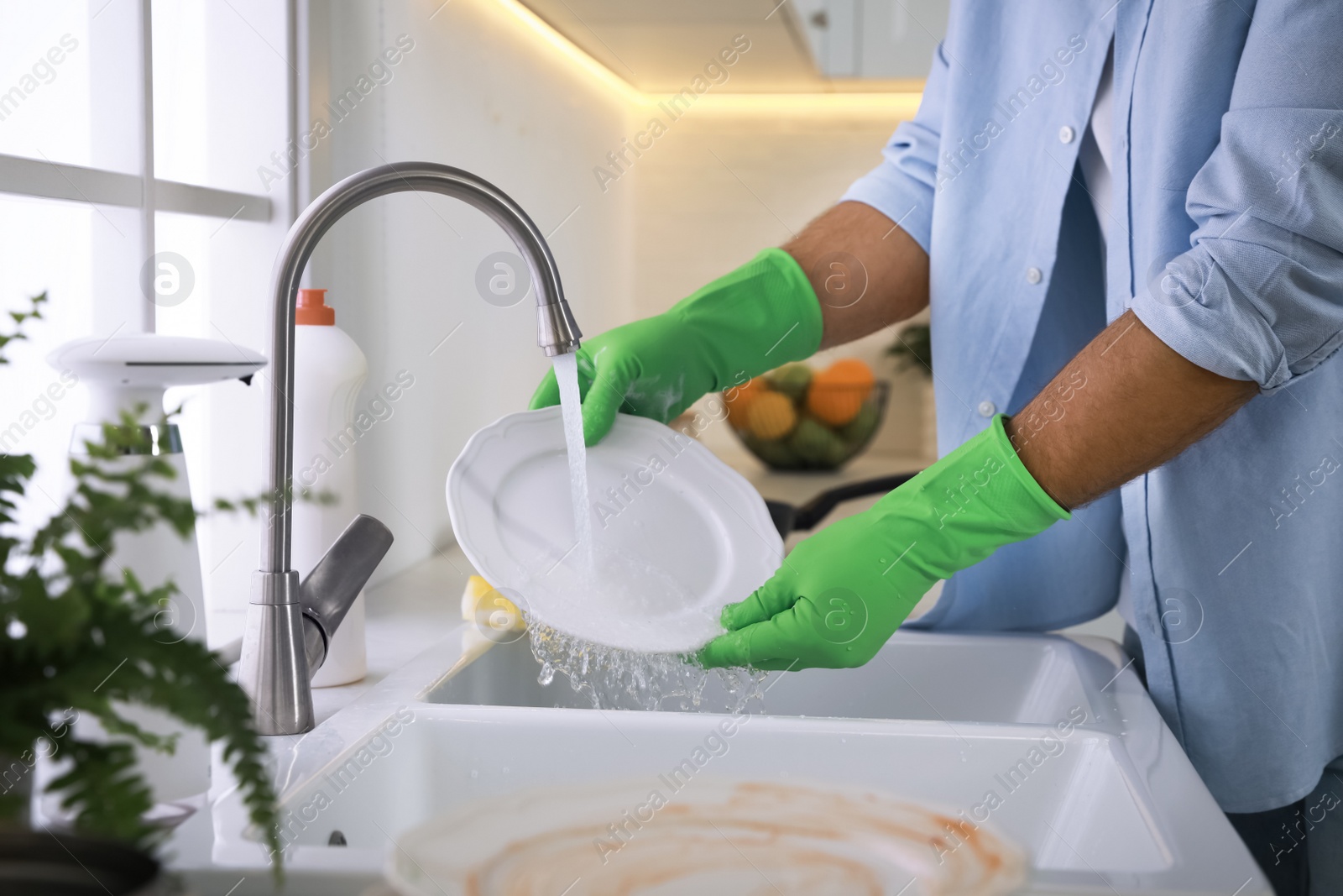 Photo of Man washing plate above sink in kitchen, closeup