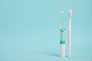 Photo of Electric and plastic toothbrushes on light blue background, space for text