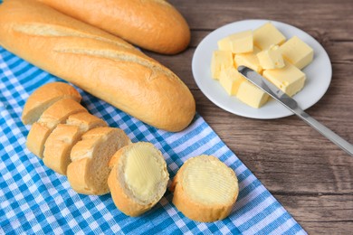 Photo of Tasty cut baguette with fresh butter on wooden table