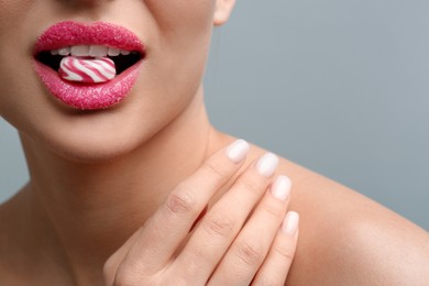 Photo of Woman with lips covered in sugar eating candy on light grey background, closeup. Space for text