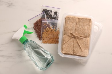 Microgreens growing kit. Different seeds, mats, containers and spray bottle on white marble table, flat lay