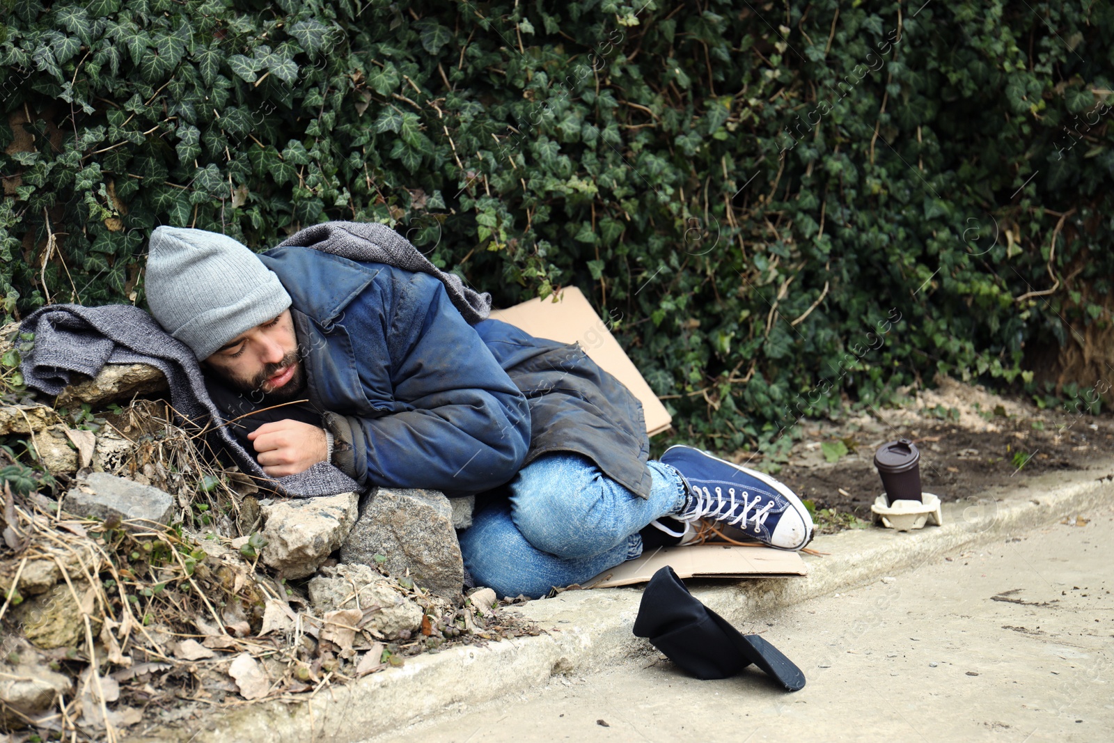 Photo of Poor homeless man lying on street in city