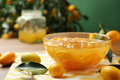 Photo of Delicious kumquat jam in bowl and fresh fruits on table, space for text