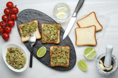 Photo of Delicious sandwiches with guacamole and ingredients on white wooden table, flat lay