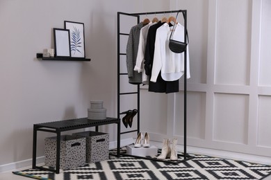 Rack with stylish women's clothes and bench in dressing room