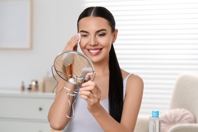 Beautiful woman removing makeup with cotton pad in room