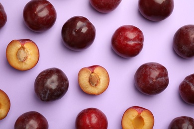 Photo of Delicious ripe plums on violet background, flat lay