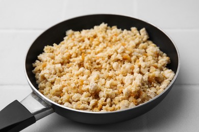 Photo of Fried ground meat in frying pan on white tiled table, closeup
