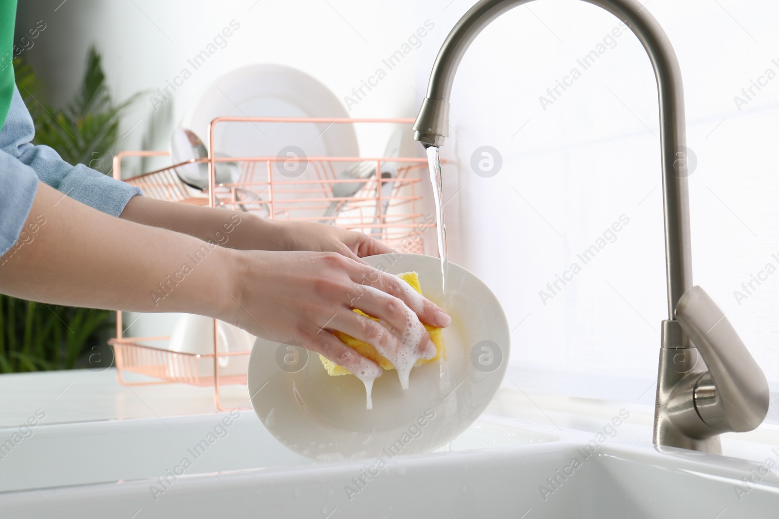 Photo of Woman washing plate in modern kitchen, closeup