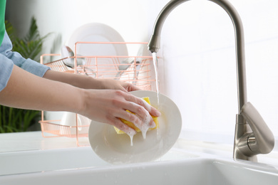 Photo of Woman washing plate in modern kitchen, closeup