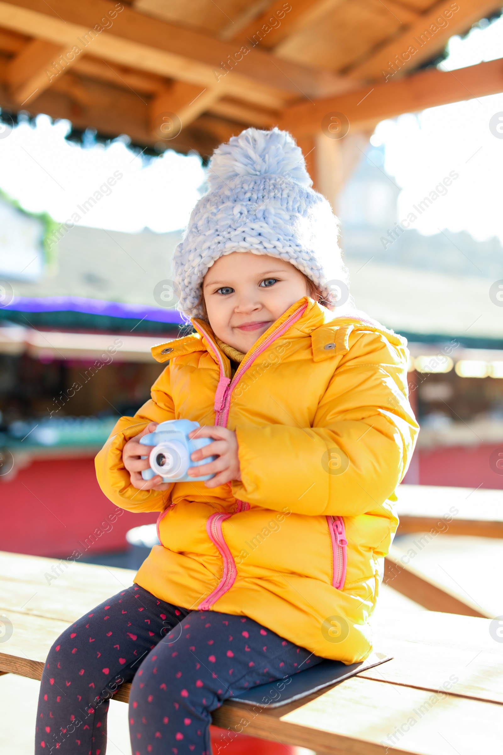 Photo of Cute little photographer with toy camera outdoors