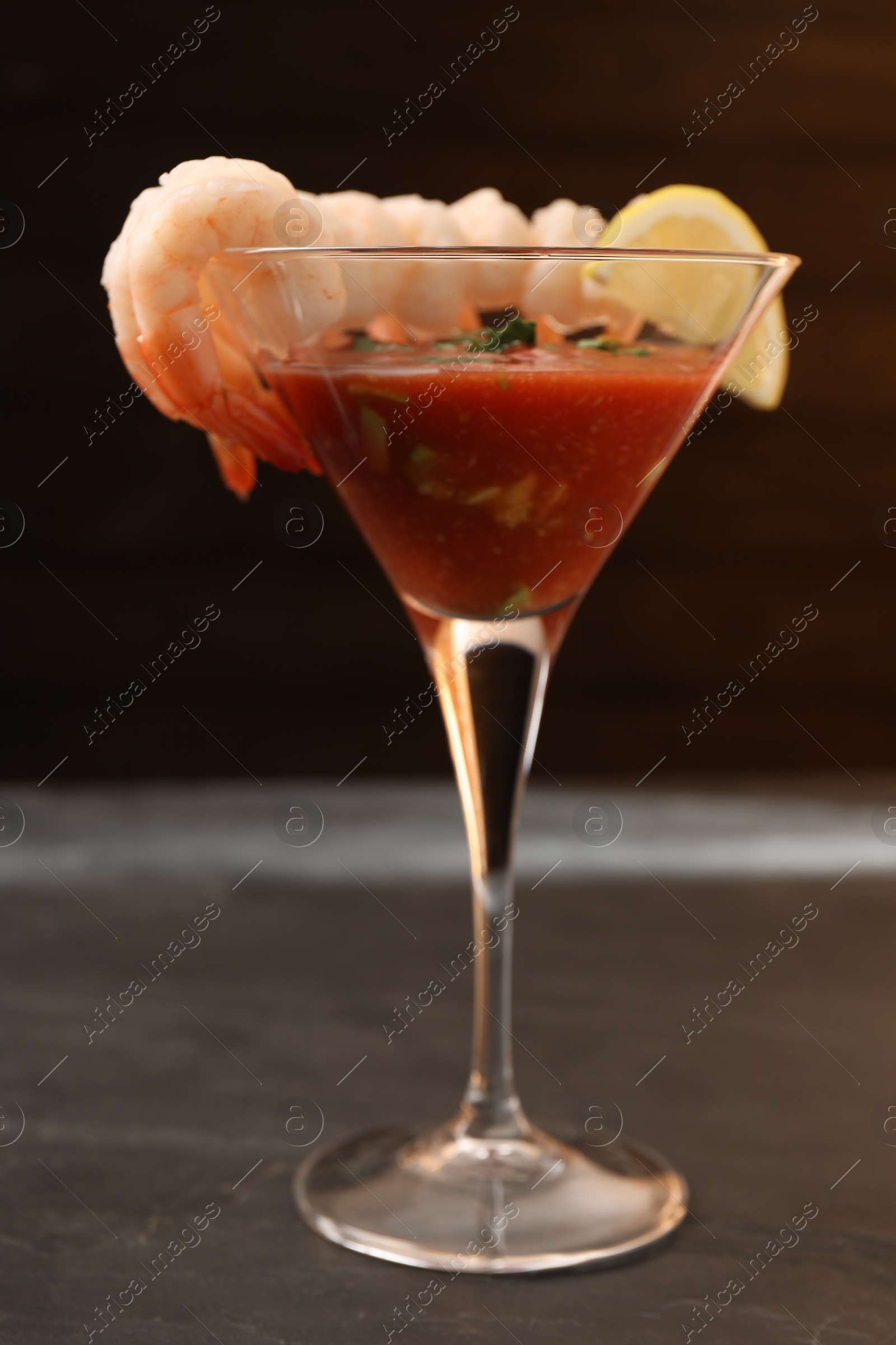 Photo of Tasty shrimp cocktail with sauce in glass on grey table closeup
