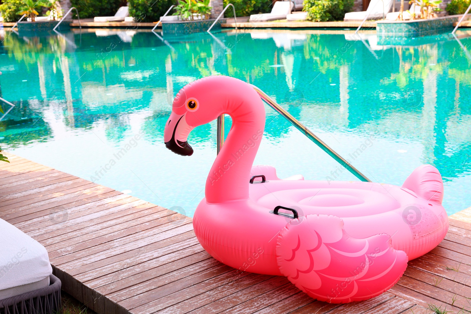 Photo of Float in shape of flamingo on wooden deck near swimming pool at luxury resort