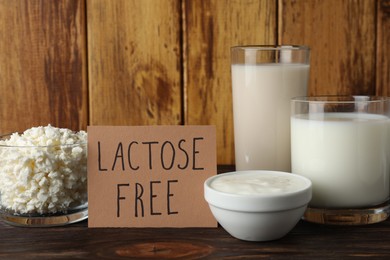 Photo of Card with phrase Lactose free and different fresh products on wooden table