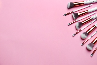 Photo of Different makeup brushes on pink background, flat lay. Space for text