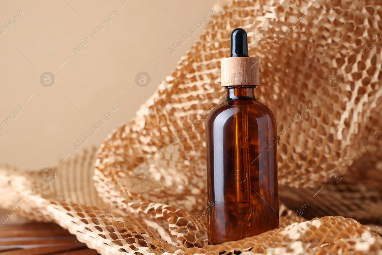 Photo of Glass bottle of cosmetic product on dark beige background, space for text