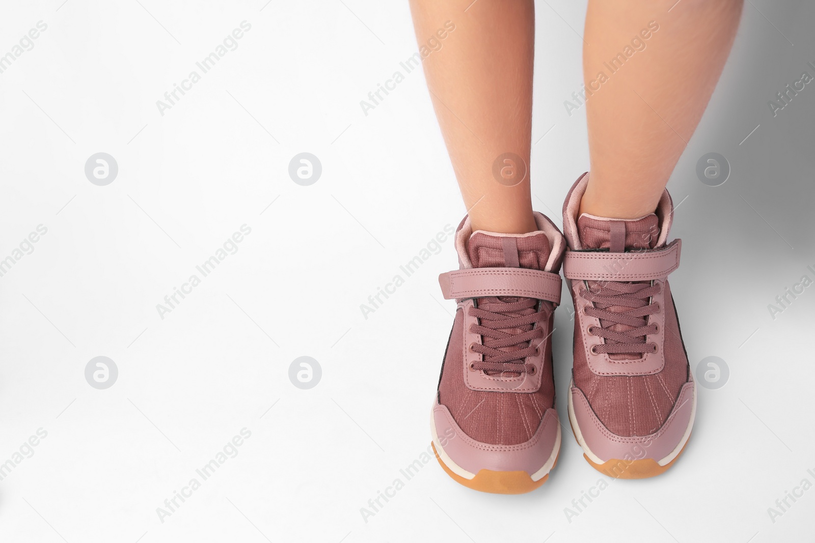 Photo of Girl wearing stylish sneakers on white background. Space for text