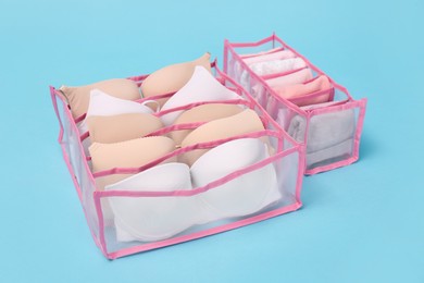 Photo of Transparent organizers with underwear on light blue background