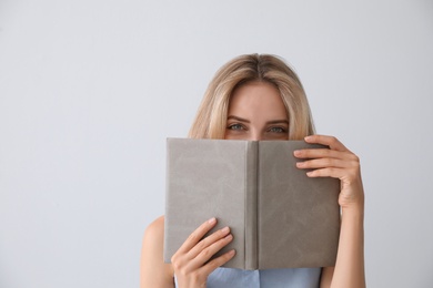 Photo of Beautiful young woman with book on light background