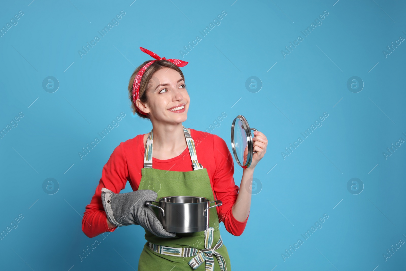 Photo of Young housewife with pot on light blue background