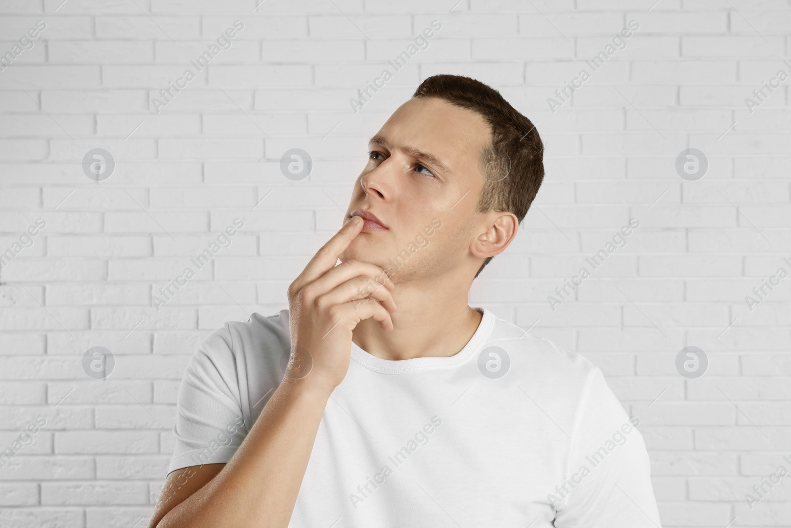 Photo of Handsome young man near white brick wall