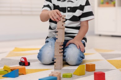 Photo of Little boy playing with wooden building blocks indoors, closeup. Child's toy