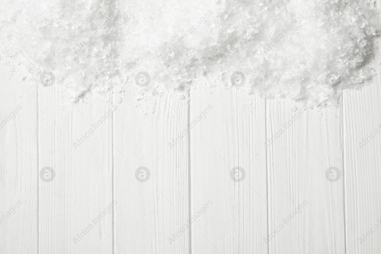 Photo of Snow and space for text on white wooden background, top view. Christmas season