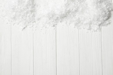 Snow and space for text on white wooden background, top view. Christmas season
