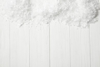 Photo of Snow and space for text on white wooden background, top view. Christmas season